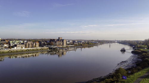 Buildings by river against sky in city