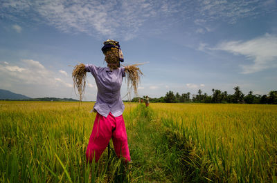 Rear view of woman standing on field against sky