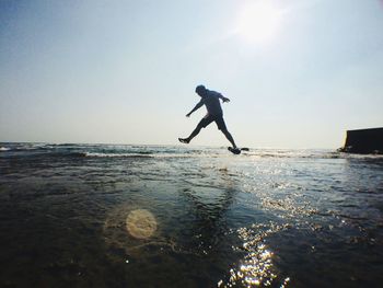 Silhouette man jumping at beach against clear sky