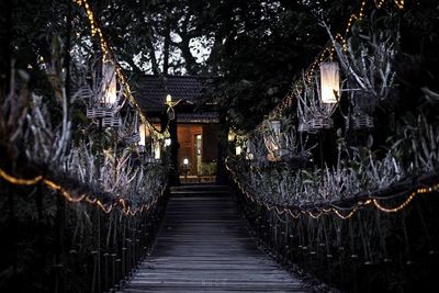 Illuminated bridge amidst trees and building at night