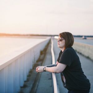 Side view of young woman standing at beach against clear sky