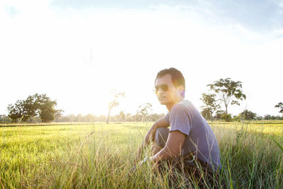 Side view of man sitting on field