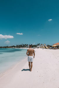 Rear view of shirtless man standing on beach