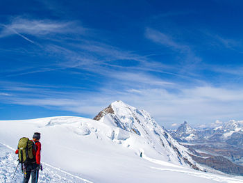 Rear view of man on snowcapped mountain against sky