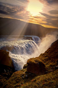 Scenic view of waterfall against sky during sunset