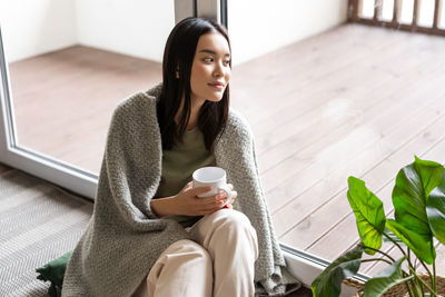 Portrait of young woman sitting on sofa at home