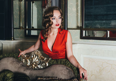 Portrait of young woman sitting against wall