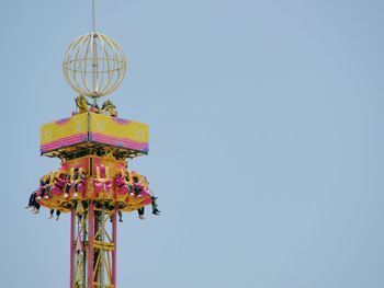 Low angle view of people enjoying free fall against clear sky