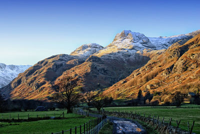 Scenic view of field and mountains against clear sky