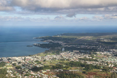 Aerial view of townscape by sea against sky