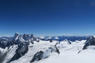 Scenic view of snowcapped mountains against clear blue sky