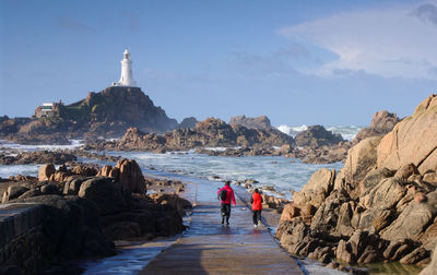 Two people walking on jetty against seascape