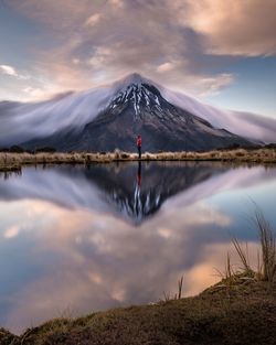 Scenic view of lake by mountains against sky during sunset