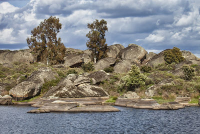 Scenic view of rocks by sea against sky