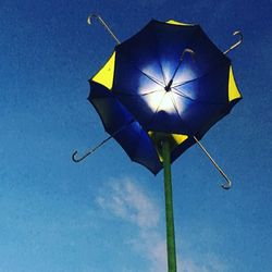 Low angle view of yellow umbrella against blue sky