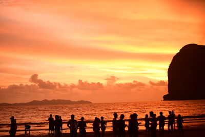 Silhouette people on beach against sky during sunset