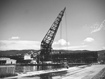 Ferris wheel by river against sky in city