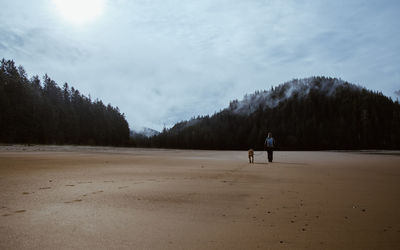 Rear view of woman with dog walking on field