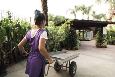 Female entrepreneur walking with wheelbarrow in garden center