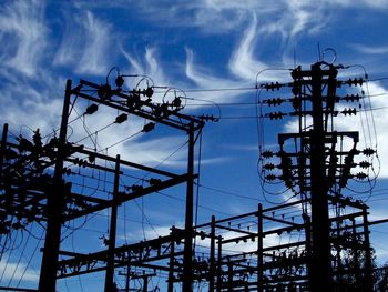 Low angle view of silhouette electricity transformer against blue sky