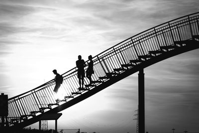 Low angle view of silhouette people walking on stairs against sky