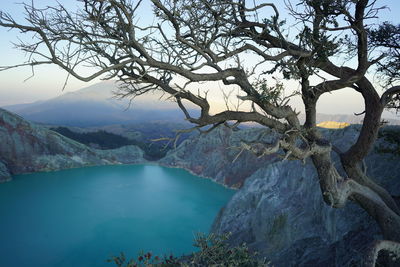 Scenic view of lake by tree mountain against sky