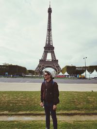 Full length portrait of woman standing against tower