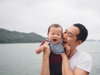 Portrait of father and daughter playing against sky