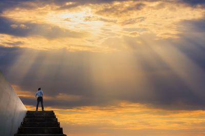 Low angle view of man standing against orange sky