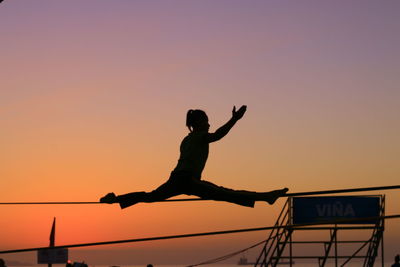 Silhouette of man with arms outstretched against sunset sky