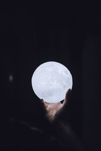 Close-up of hand holding moon over black background