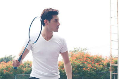 Young man playing badminton against clear sky