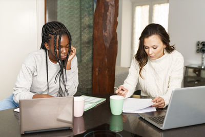 Young woman using mobile phone while sitting on table