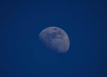 Low angle view of moon against clear blue sky