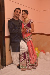 Portrait of couple in traditional clothing standing against wall