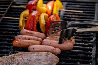 Barbecue close up. grilling meat and vegetables. grill tongs flip sausages. summer leisure outdoors.