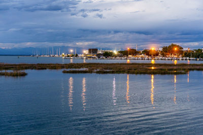 Sunset over the small sea harbour with blue clouds and lights reflection in the water