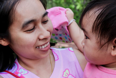 Close-up of smiling woman holding baby girl