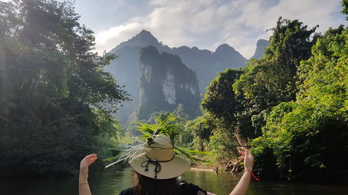 Rear view of woman in lake against trees and sky