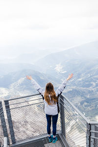 Rear view of woman standing on mountain against sky