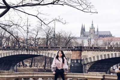 Young woman sitting against bridge in city