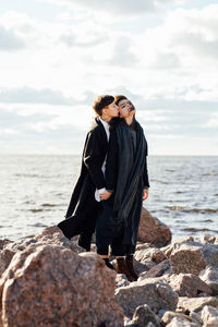 Woman standing on rock at beach against sky