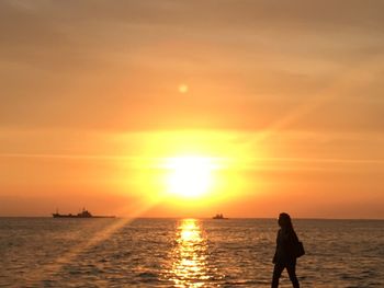 Silhouette people on beach against sky during sunset