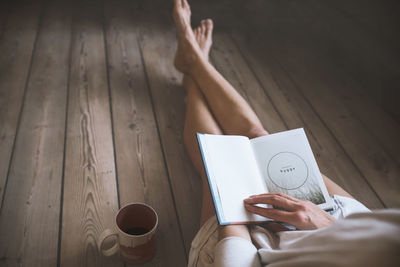 Midsection of woman holding coffee cup on table