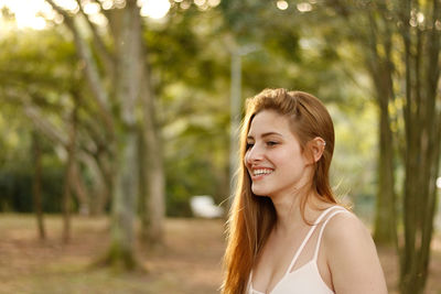 Smiling young woman against trees