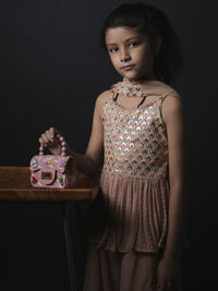 Portrait of young woman standing against wall