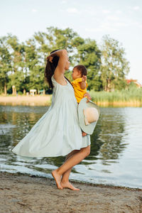 Young woman standing by lake against sky