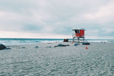 Lifeguard hut on beach against cloudy sky
