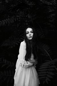 Portrait of young woman standing against wall