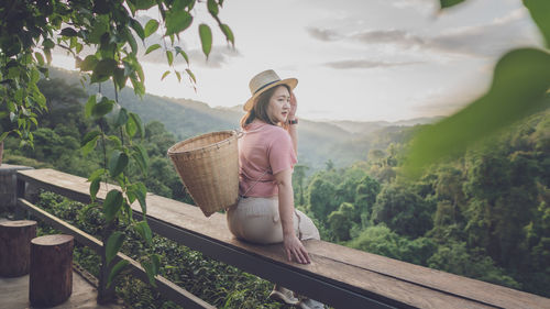 Woman carrying basket while sitting on railing